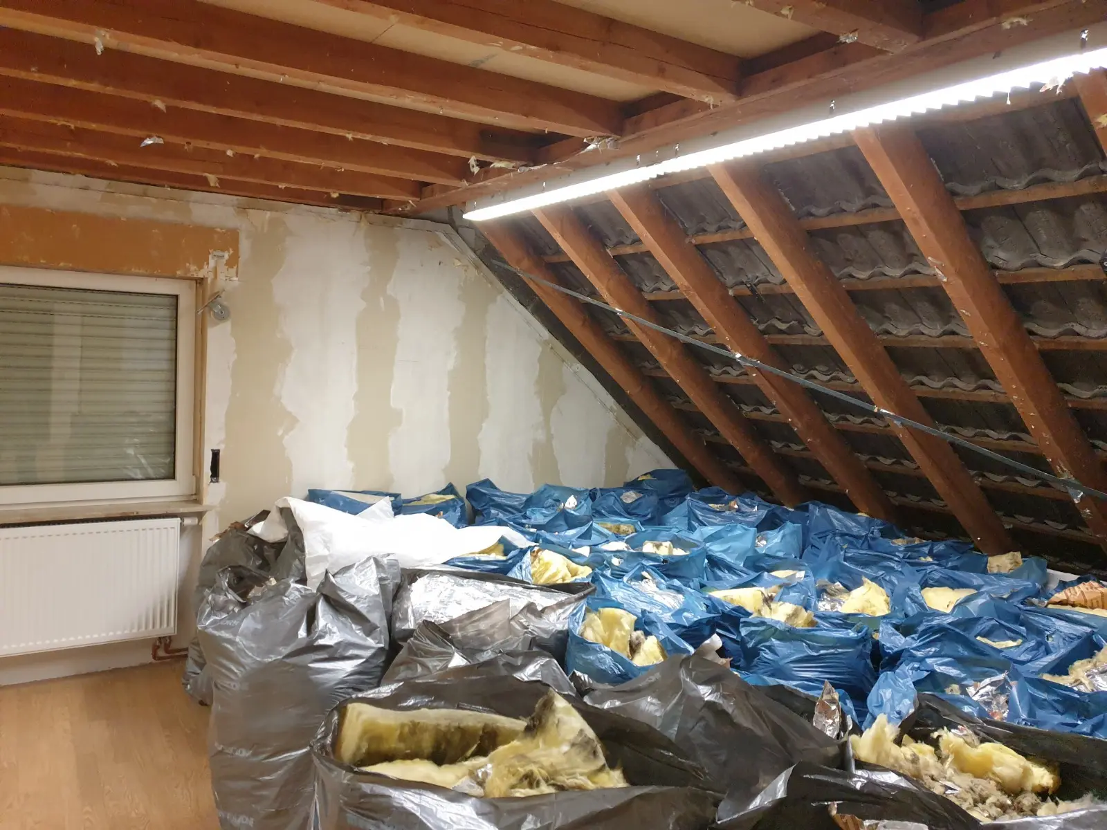 Ausgebaute alte Dämmung in Säcken auf dem Dachboden